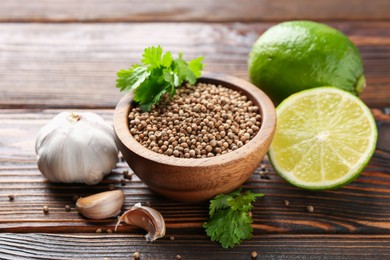 Photo of Coriander seeds, fresh cilantro, lime and garlic on wooden table, closeup