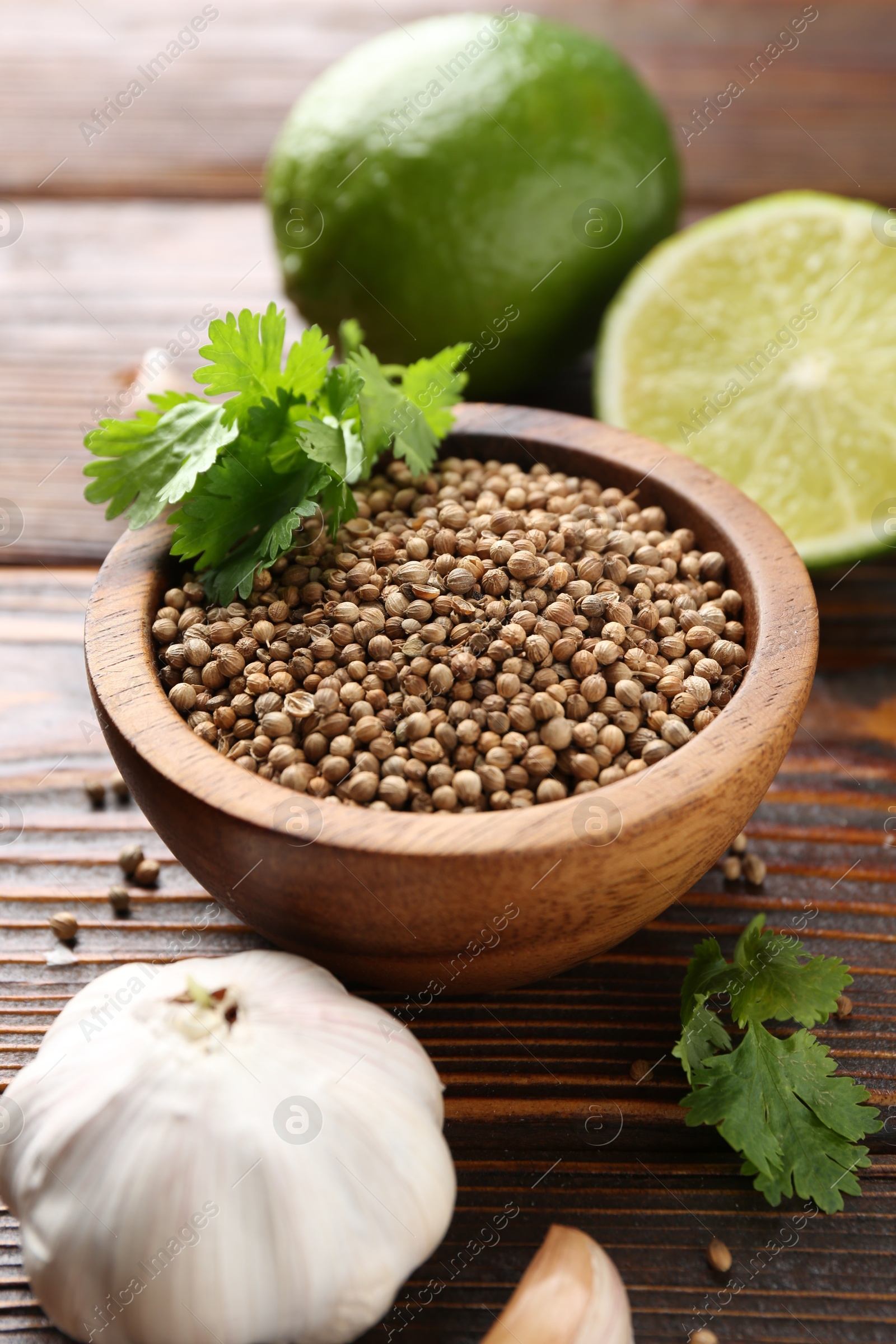 Coriander seeds, fresh cilantro, lime and garlic on wooden table, closeup Photo of Coriander seeds, fresh cilantro, lime and garlic on wooden table, closeup
