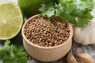 Photo of Coriander seeds, fresh cilantro, lime and garlic on grey textured table, closeup