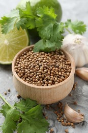 Photo of Coriander seeds, fresh cilantro, lime and garlic on grey textured table, closeup