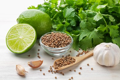 Photo of Coriander seeds, fresh cilantro, lime and garlic on light wooden table, closeup