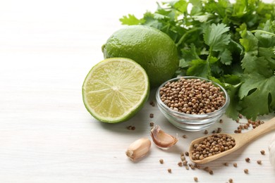 Photo of Coriander seeds, fresh cilantro, lime and garlic on light wooden table, closeup