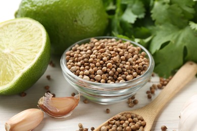 Photo of Coriander seeds, fresh cilantro, lime and garlic on light wooden table, closeup