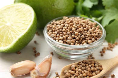 Photo of Coriander seeds, fresh cilantro, lime and garlic on light wooden table, closeup