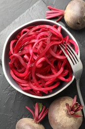 Photo of Raw beetroot noodles and fresh vegetables on black table, flat lay. Vegetarian dish
