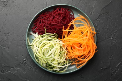 Photo of Different vegetable noodles on black table, top view. Vegetarian dish