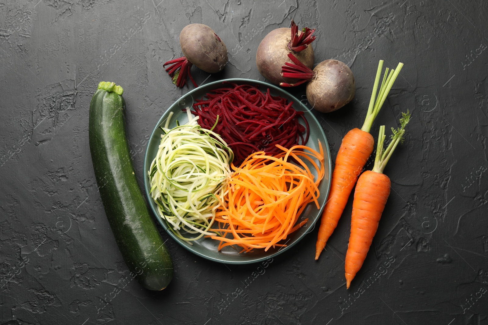Photo of Different vegetable noodles on black table, flat lay. Vegetarian dish