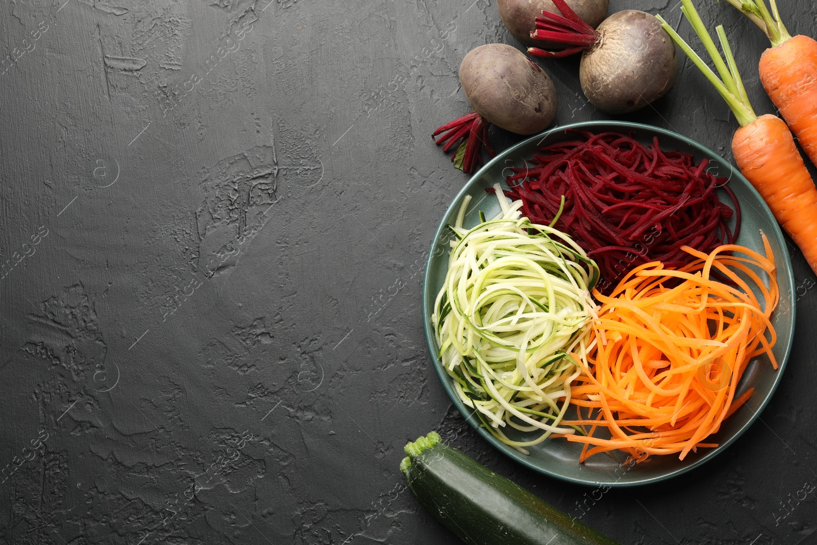 Vegetarian dish. Different vegetable noodles on black table, flat lay. Space for text Photo of Vegetarian dish. Different vegetable noodles on black table, flat lay. Space for text