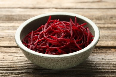 Photo of Raw beetroot noodles in bowl on wooden table, closeup. Vegetarian dish