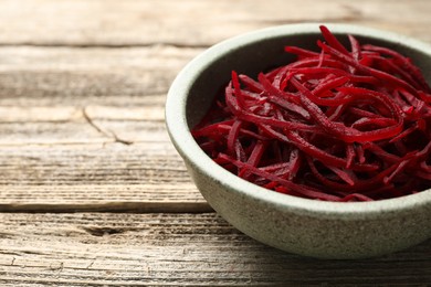 Photo of Vegetarian dish. Raw beetroot noodles in bowl on wooden table, closeup. Space for text