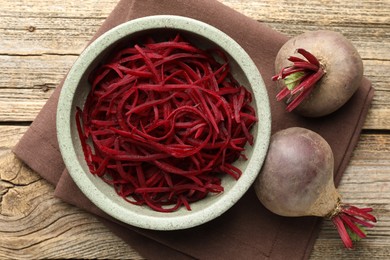 Photo of Raw beetroot noodles and fresh vegetables on wooden table, flat lay. Vegetarian dish