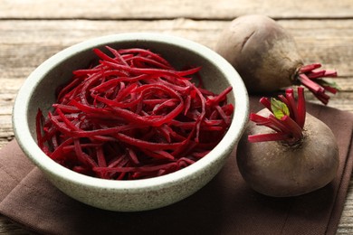 Photo of Raw beetroot noodles and fresh vegetables on wooden table, closeup. Vegetarian dish