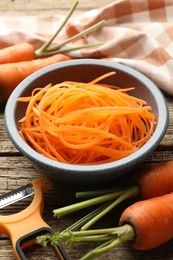 Photo of Raw beetroot noodles, fresh vegetables and peeler on wooden table, closeup. Vegetarian dish