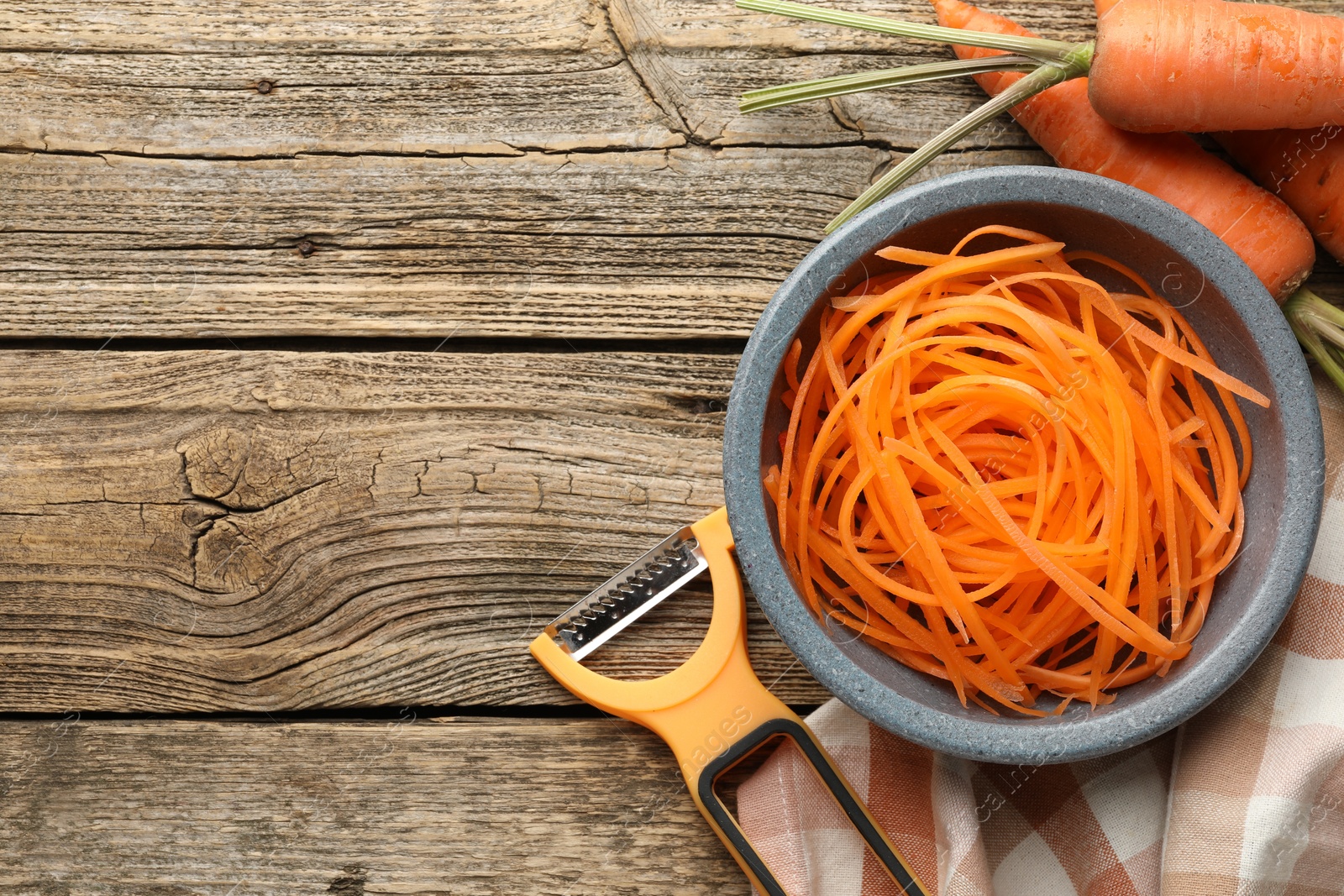Photo of Vegetarian dish. Raw beetroot noodles, fresh vegetables and peeler on wooden table, flat lay. Space for text