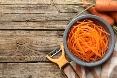 Photo of Vegetarian dish. Raw beetroot noodles, fresh vegetables and peeler on wooden table, flat lay. Space for text