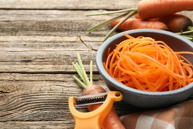 Photo of Vegetarian dish. Raw beetroot noodles, fresh vegetables and peeler on wooden table, closeup. Space for text