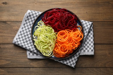 Photo of Different vegetable noodles on wooden table, top view. Vegetarian dish