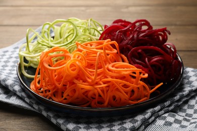 Photo of Different vegetable noodles on wooden table, closeup. Vegetarian dish