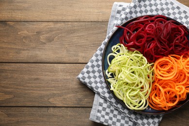 Photo of Vegetarian dish. Different vegetable noodles on wooden table, top view. Space for text