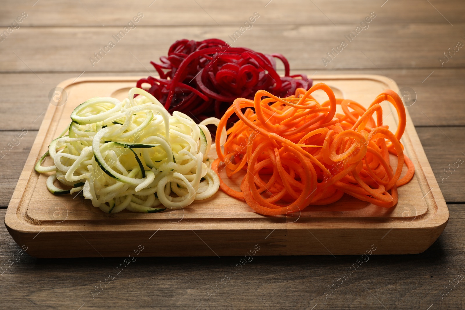 Photo of Different vegetable noodles on wooden table, closeup. Vegetarian dish