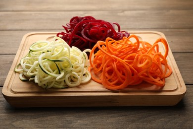 Photo of Different vegetable noodles on wooden table, closeup. Vegetarian dish