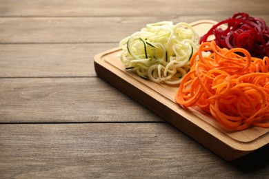 Photo of Vegetarian dish. Different vegetable noodles on wooden table, closeup. Space for text