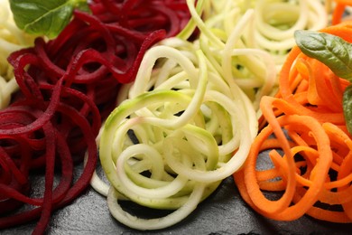 Photo of Different vegetable noodles with basil on table, closeup. Vegetarian dish