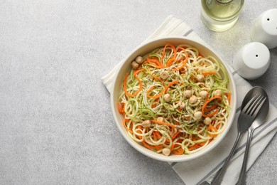 Photo of Vegetarian dish. Tasty vegetable noodles with chickpeas served on grey table, flat lay. Space for text