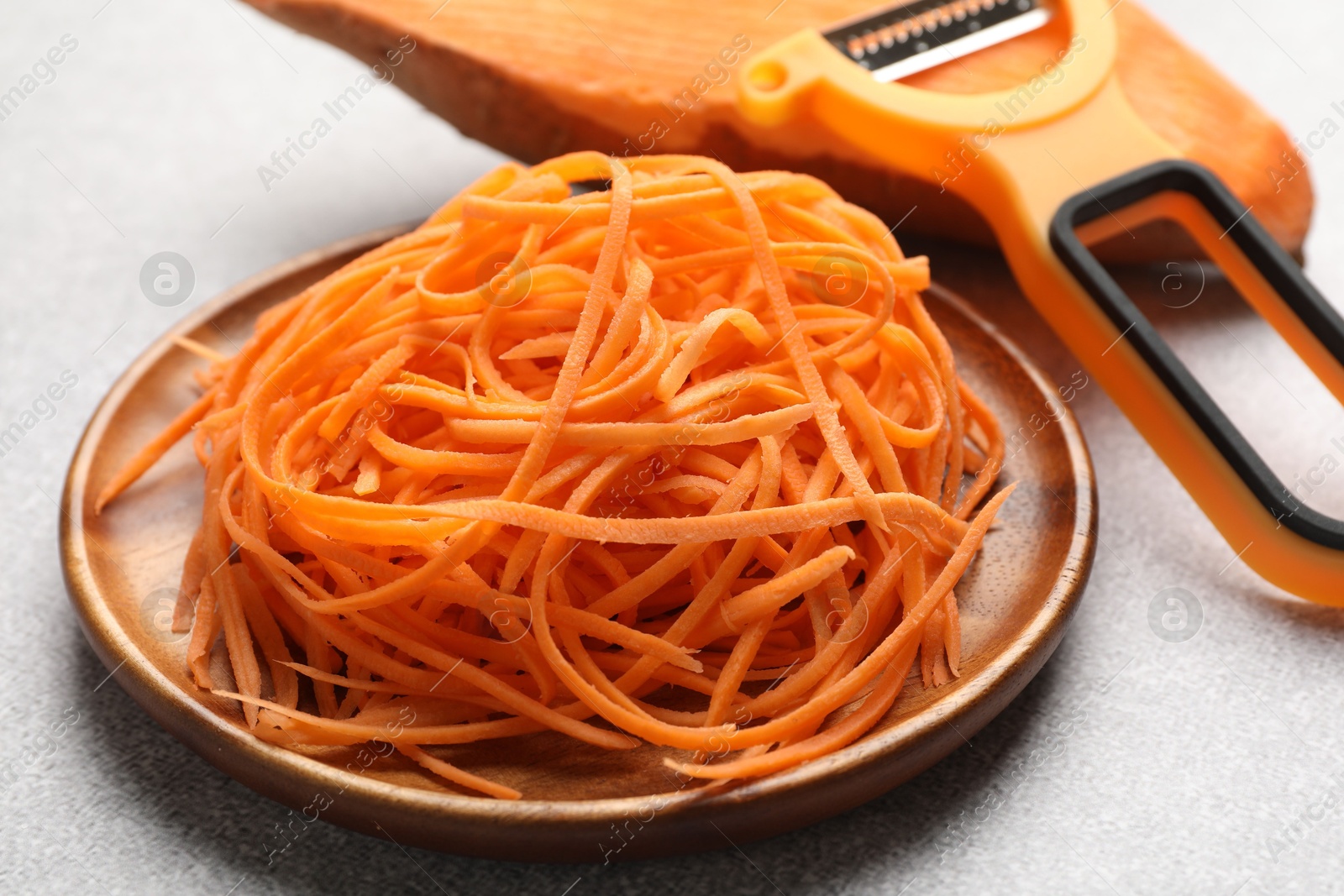 Photo of Vegetable noodles, sweet potato and peeler on light table, closeup