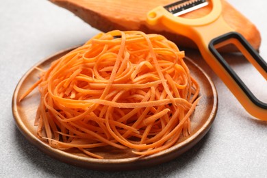 Photo of Vegetable noodles, sweet potato and peeler on light table, closeup