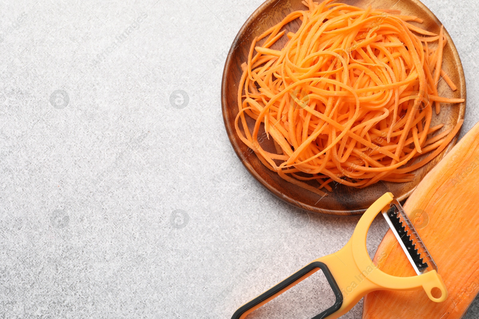 Photo of Vegetable noodles, sweet potato and peeler on light table, flat lay. Space for text