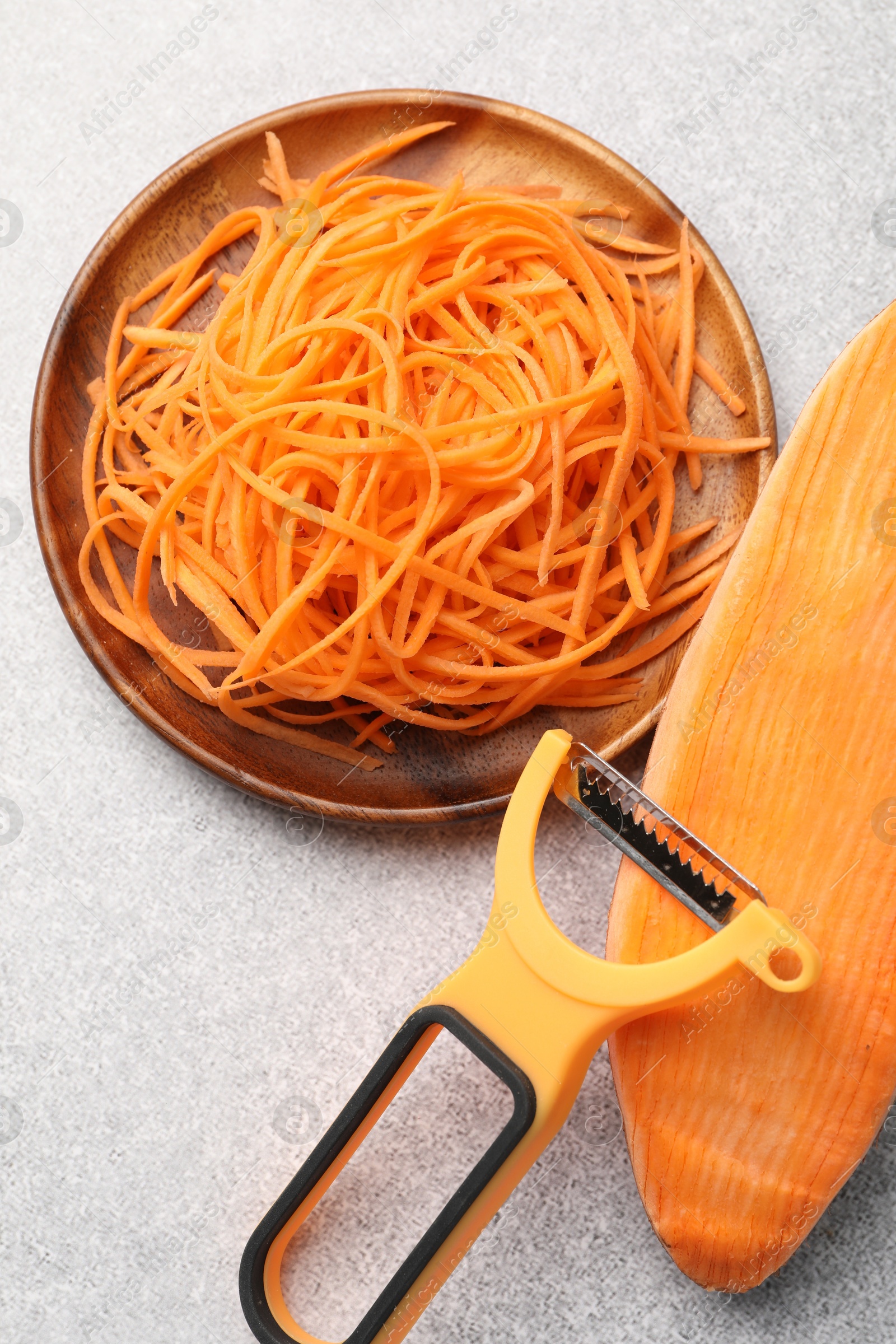 Vegetable noodles, sweet potato and peeler on light table, flat lay Photo of Vegetable noodles, sweet potato and peeler on light table, flat lay