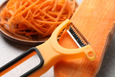 Photo of Vegetable noodles, sweet potato and peeler on light table, closeup