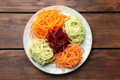 Photo of Different vegetable noodles on wooden table, top view