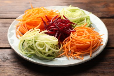 Photo of Different vegetable noodles on wooden table, closeup