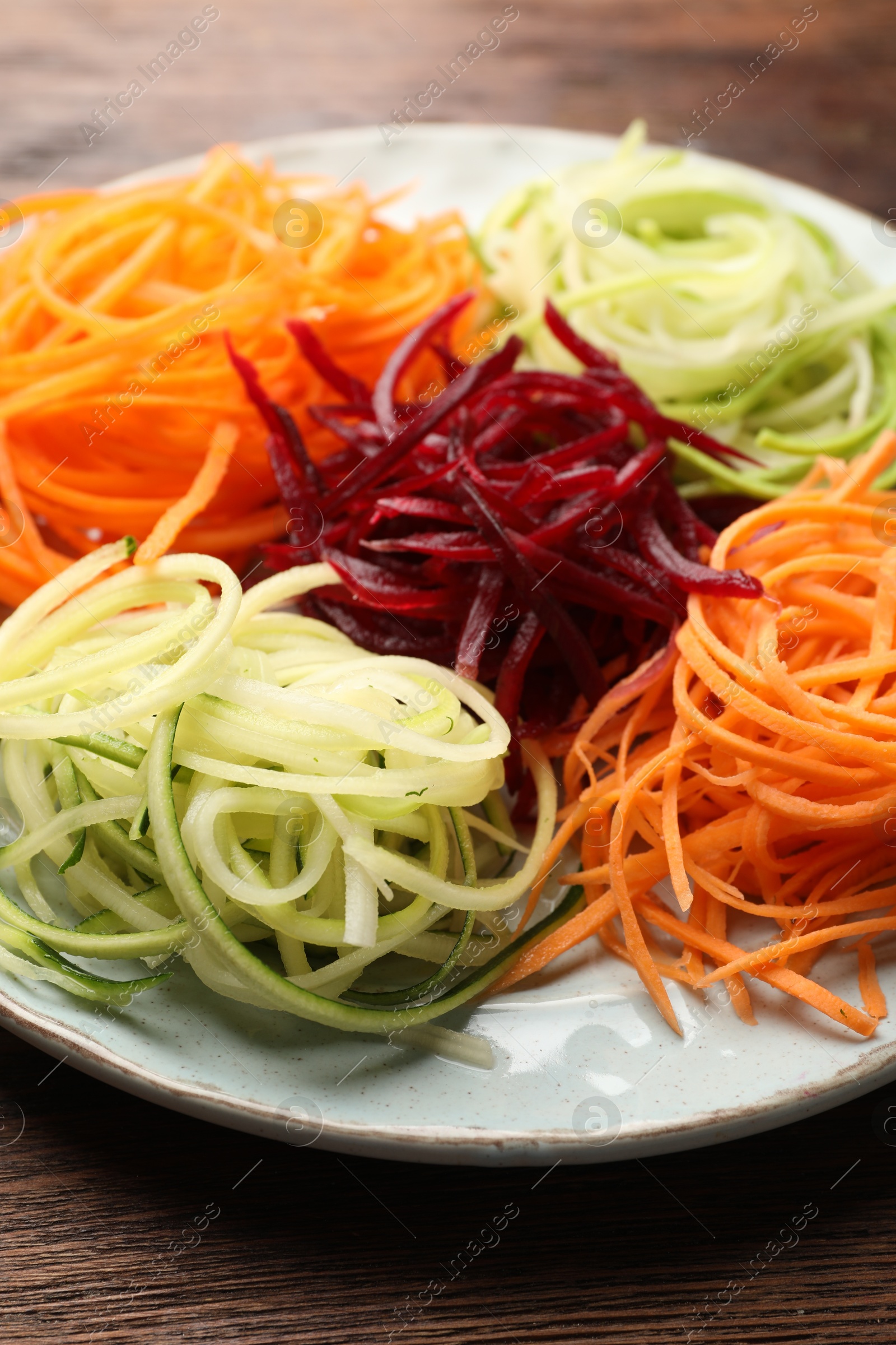 Photo of Different vegetable noodles on wooden table, closeup