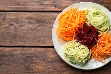 Photo of Different vegetable noodles on wooden table, top view. Space for text