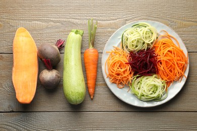 Photo of Different noodles and vegetables on wooden table, flat lay