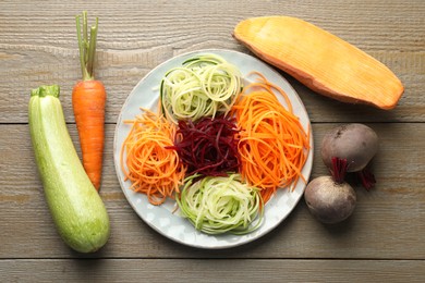 Photo of Different noodles and vegetables on wooden table, flat lay