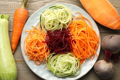 Photo of Different noodles and vegetables on wooden table, flat lay