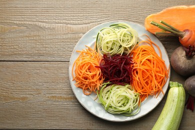 Photo of Different noodles and vegetables on wooden table, flat lay. Space for text