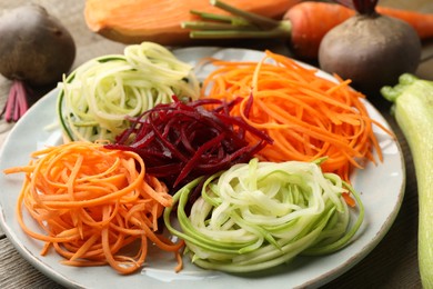 Photo of Different noodles and vegetables on wooden table, closeup