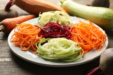 Photo of Different noodles and vegetables on wooden table, closeup