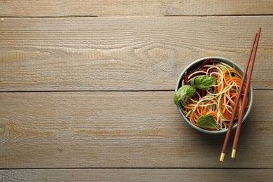 Photo of Tasty vegetable noodles served on wooden table, top view. Space for text