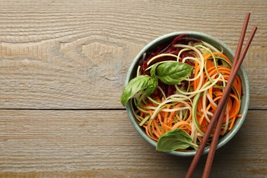 Photo of Tasty vegetable noodles served on wooden table, top view. Space for text