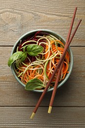 Photo of Tasty vegetable noodles served on wooden table, top view