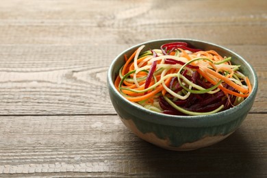 Photo of Tasty vegetable noodles on wooden table, closeup. Space for text