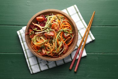 Photo of Tasty vegetable noodles served on green wooden table, top view