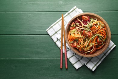 Photo of Tasty vegetable noodles served on green wooden table, top view. Space for text