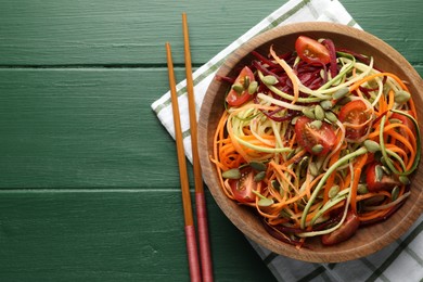 Photo of Tasty vegetable noodles served on green wooden table, top view. Space for text